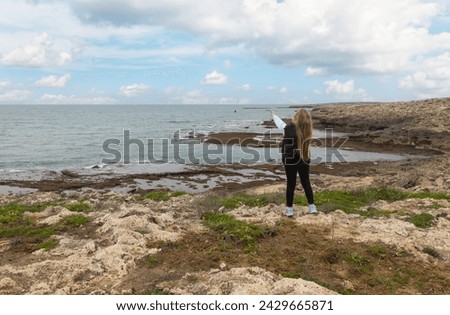 A girl on the shore of the Mediterranean Sea in Israel points her hand into the distance