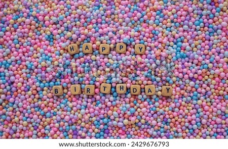 Happy birthday text on background from small colourful spheres balls.
