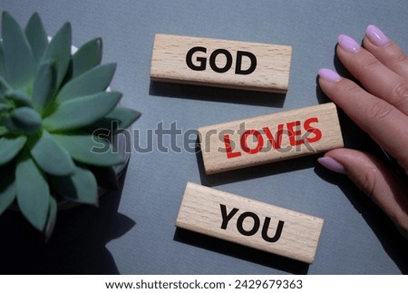 God loves you symbol. Wooden blocks with words God loves you. Beautiful grey background with succulent plant. Prayer hand. Religion and God loves you concept. Copy space.