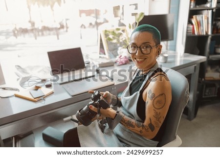 Female designer in eyeglasses use camera during working in own design studio