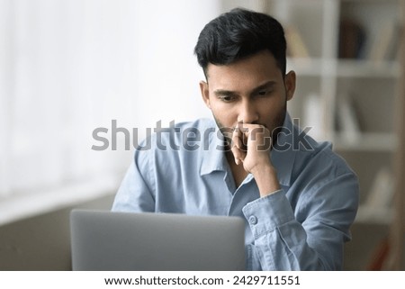 Serious concentrated Indian businessman staring at laptop screen think over business issue, read email with unpleasant new, make decision, search solution, ponder of startup plan, learns new program
