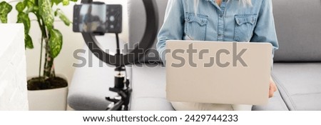 side view of young woman using smartphone at table with laptop