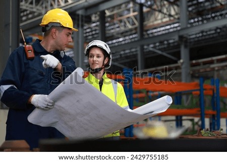 Male and female rail engineer working with blueprint drawing in electric train garage  Royalty-Free Stock Photo #2429755185