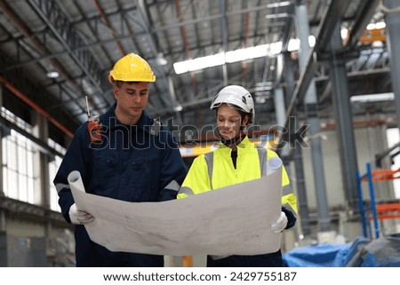 Male and female rail engineer working with blueprint drawing in electric train garage  Royalty-Free Stock Photo #2429755187