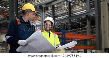 Male and female rail engineer working with blueprint drawing in electric train garage  Royalty-Free Stock Photo #2429755191