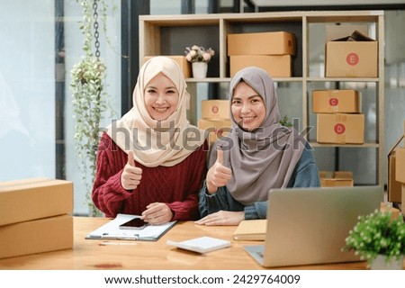 Friend muslim female two work business sme online shopping working on laptop computer with parcel box on desk at home, SME online business and delivery concept