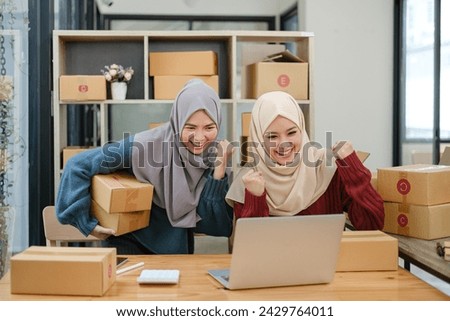 Friend muslim female two work business sme online shopping working on laptop computer with parcel box on desk at home, SME online business and delivery concept