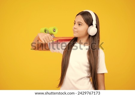 Beautiful and fashion young teen girl posing with skateboard and headphones. Teenager street fashion lifestyle.