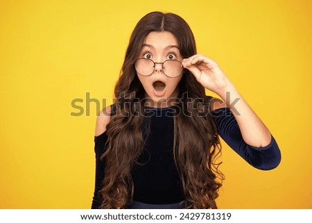 Surprised teenager girl. Shocked amazed face. Portrait of teenager child in glasses. Kid at eye sight test. Girl holding eyeglasses and looking at camera. Eyesight measurement for school children.