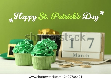 Happy St. Patrick's day card. Cupcakes, pot of gold and wooden block calendar with date - March 17 on white table