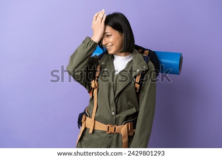 Young mountaineer woman with a big backpack over isolated background has realized something and intending the solution