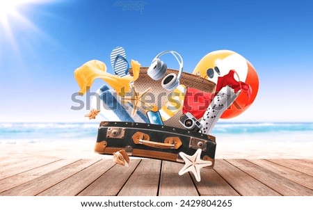 Flying open suitcase with accessories and beach in the background: summer vacations and travel concept