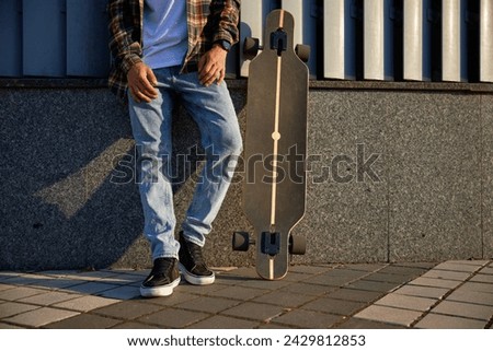 Hipster guy with skateboard enjoying summer day crop view