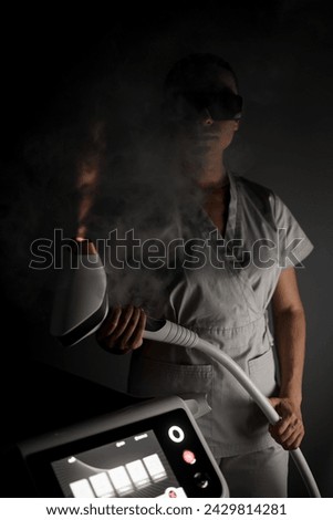 Female laser hair removal specialist stands in the middle of smoke in protective glasses, holds a photo epilator with an upward laser plume Royalty-Free Stock Photo #2429814281