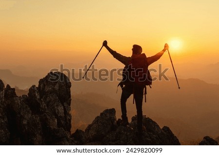 Happy male traveler relaxing and watching the sunset on the mountain top