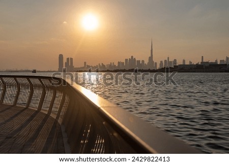 A picture of Downtown Dubai at sunset, as seen from afar, with the Burj Khalifa towering all high rises.