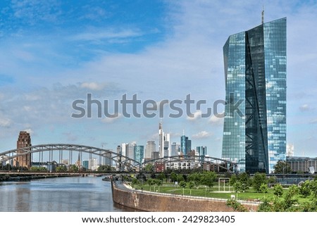 The glass façade of the modern high-rise of the European Central Bank (ECB) in Frankfurt am Main in fine weather with the skyline of the city in the background Royalty-Free Stock Photo #2429823405