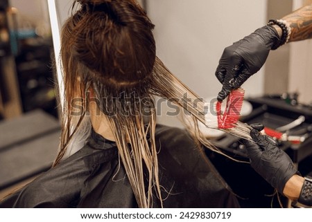 Close up of colorist dyes hair of woman with brush and foil in beauty salon Royalty-Free Stock Photo #2429830719