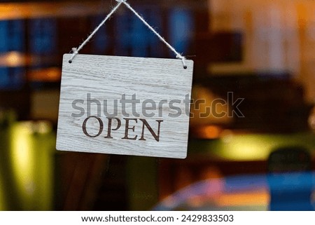 Open business wooden sign hanging in a shop window