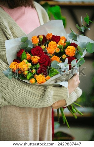 A woman gracefully holds a bouquet of flowers in her hands, creating a beautiful and serene image.