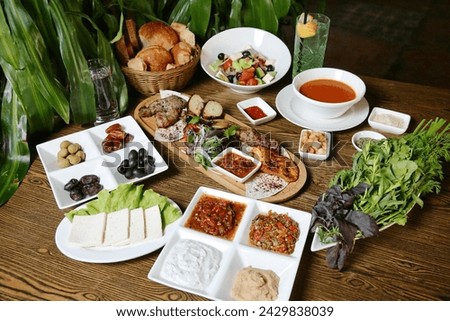 A wooden table adorned with an assortment of delectable dishes, including savory entrees, fresh salads, and delectable desserts. Royalty-Free Stock Photo #2429838039