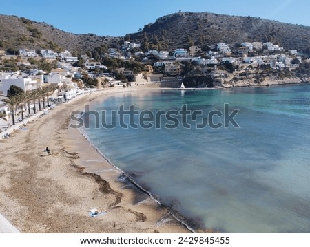 Photo of Moraira cove, you can see the beach in the foreground and the transparent waters, in the background the houses on the mountain, a beautiful tourist destination in Spain.