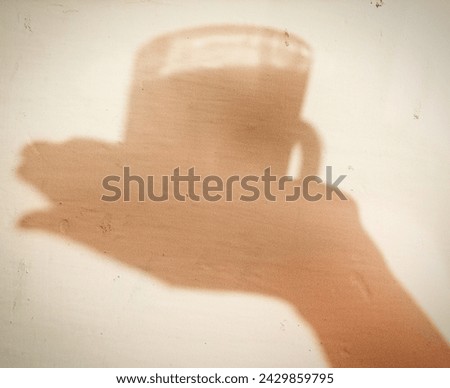 Shadow of a cup of tea on hand and 3D picture of tea cup