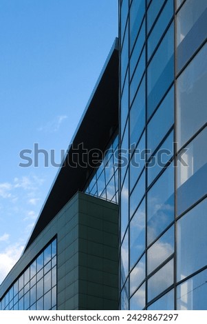 Wall of a modern building with full length windows and reflections of clouds in the glass