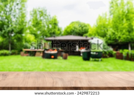 summer concept with wood table top backyard garden with grill BBQ, wooden table, blurred background,  Royalty-Free Stock Photo #2429872213