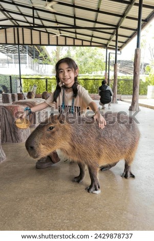 Happy children play joyfully outdoors with their capybara