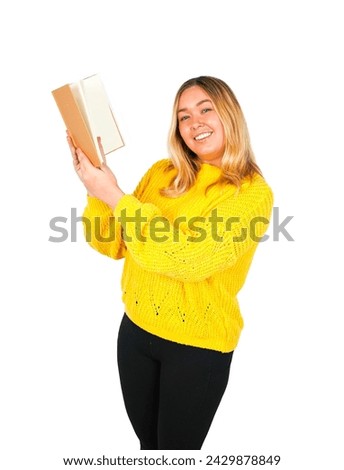 Happy young blonde female teacher holding a brown book while wearing a yellow jumper against a white background