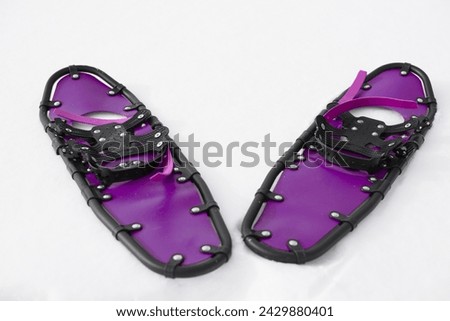 young sportsman walks in purple snowshoes and leggings on snow, close-up view of legs, winter hiking concept, active lifestyle