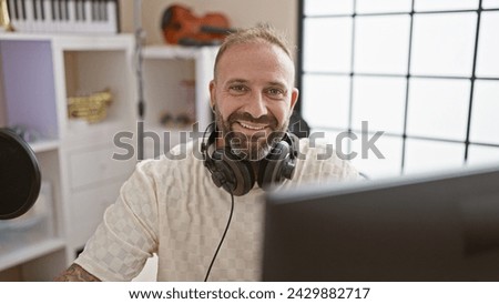 Charming young musician, headphones caressing his ears, gracing a music studio with his infectious smile - an upbeat blend of melody, relaxation, and confidence. Royalty-Free Stock Photo #2429882717