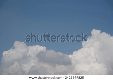 Beautiful white clouds against the blue sky. Blue sky at top and a white clound at bottom of shot.
