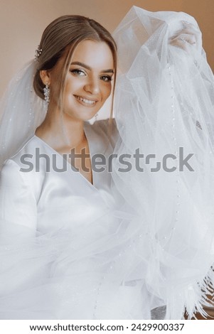 portrait of an incredibly beautiful girl bride in a white robe in the bedroom, the bride poses in the morning before the wedding ceremony.