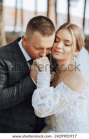 The groom kisses the bride's hand. Wedding photo of a couple in love. A young and handsome man kissing his wife's hand with a gold ring, proposing. Royalty-Free Stock Photo #2429901917