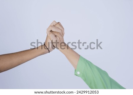 A close-up of a young man and woman's hands clasped together, symbolizing love, affection and support, isolated in a gray background. Royalty-Free Stock Photo #2429912053