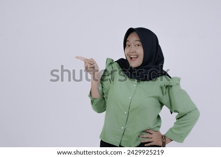 Cheerful excited asian woman use finger pointing to side with product or empty copy space standing over isolated white background. Model young girl laughing promotion. Advertisement presenting concept