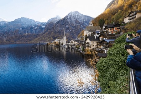 Tourists Capturing the Scenic Beauty of an Alpine Village by the Lake in 
