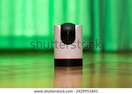 CCTV camera operating in home. Surveillance camera to protect and monitor your home through a mobile application. Home Security System Concept. smart camera on wooden table. 360 degrees rotating head Royalty-Free Stock Photo #2429951841