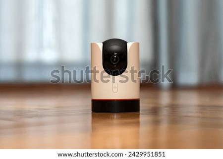 CCTV camera operating in home. Surveillance camera to protect and monitor your home through a mobile application. Home Security System Concept. smart camera on wooden table. 360 degrees rotating head Royalty-Free Stock Photo #2429951851
