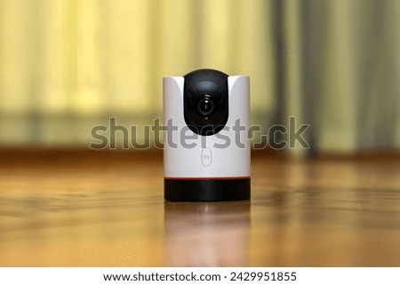 CCTV camera operating in home. Surveillance camera to protect and monitor your home through a mobile application. Home Security System Concept. smart camera on wooden table. 360 degrees rotating head Royalty-Free Stock Photo #2429951855