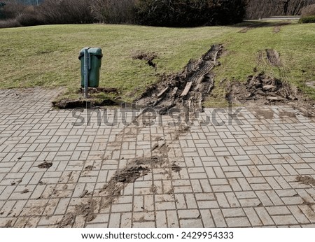 spring rains waterlogged the soil profile and lawns and meadows are mud traps for heavy vehicles. impenetrable by spring snowmelt. the rutted tracks of car that came back, trash, garbage can, bin Royalty-Free Stock Photo #2429954333