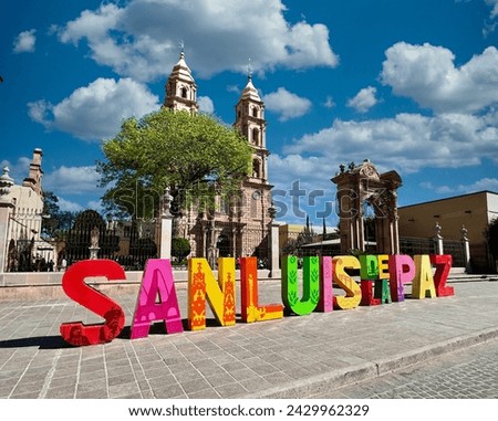 Iconic San Luis de la Paz sign with the historic San Luis Rey Parish in the background, captured on a sunny afternoon. sstkMexicanCulture