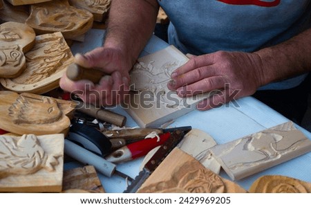 wooden pictures are cut of small pieces of wood by a male craftsman.