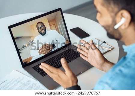 american man talking using webcam internet connection. Millennial indian arabian student speaking with teacher business coach mentor sitting at home desk. Video conference app. View over shoulder Royalty-Free Stock Photo #2429978967