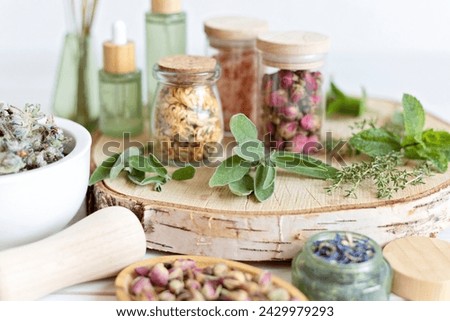 A wooden tray holds an assortment of herbal skincare items and dried flowers, presenting a natural, organic aesthetic for beauty and self-care