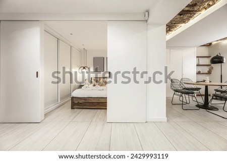 Bedroom with double bed with white wooden double sliding doors, modern decoration in an apartment with industrial style furniture