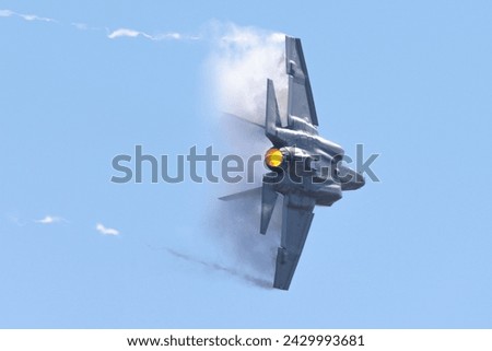 Very unusual close tail view of a F-35C Lightning II  at very high speed, in a  condensation cone (“singularity”) and trails at the wing tips Royalty-Free Stock Photo #2429993681