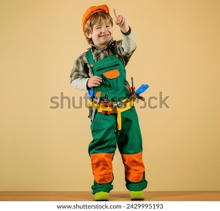 Cute kid repairman in protective helmet with toolbelt of toy tools for building. Happy child boy in uniform and hard hat with builder tools set. Little child builder playing with toy tools for repair. Royalty-Free Stock Photo #2429995193
